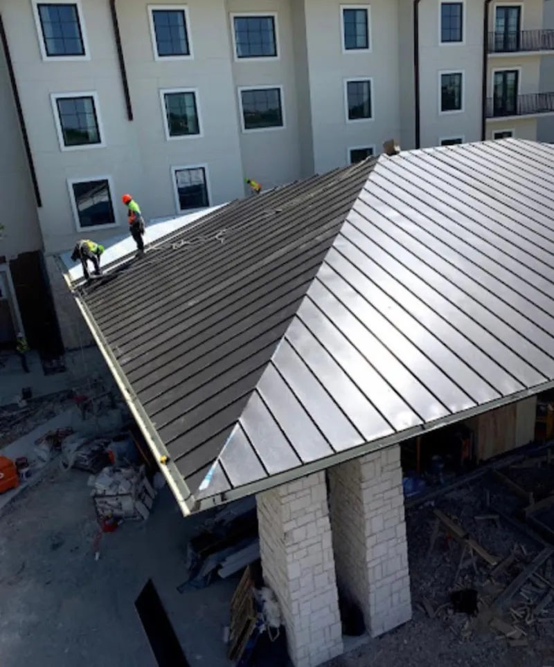 Crew installing standing seam metal roof panels on a commercial project in California City